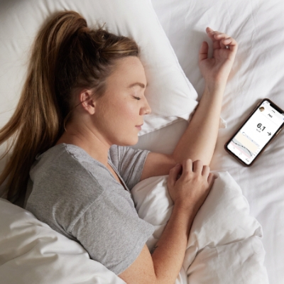 Teenage girl with paediatric diabetes asleep in bed next to phone with Dexcom App open